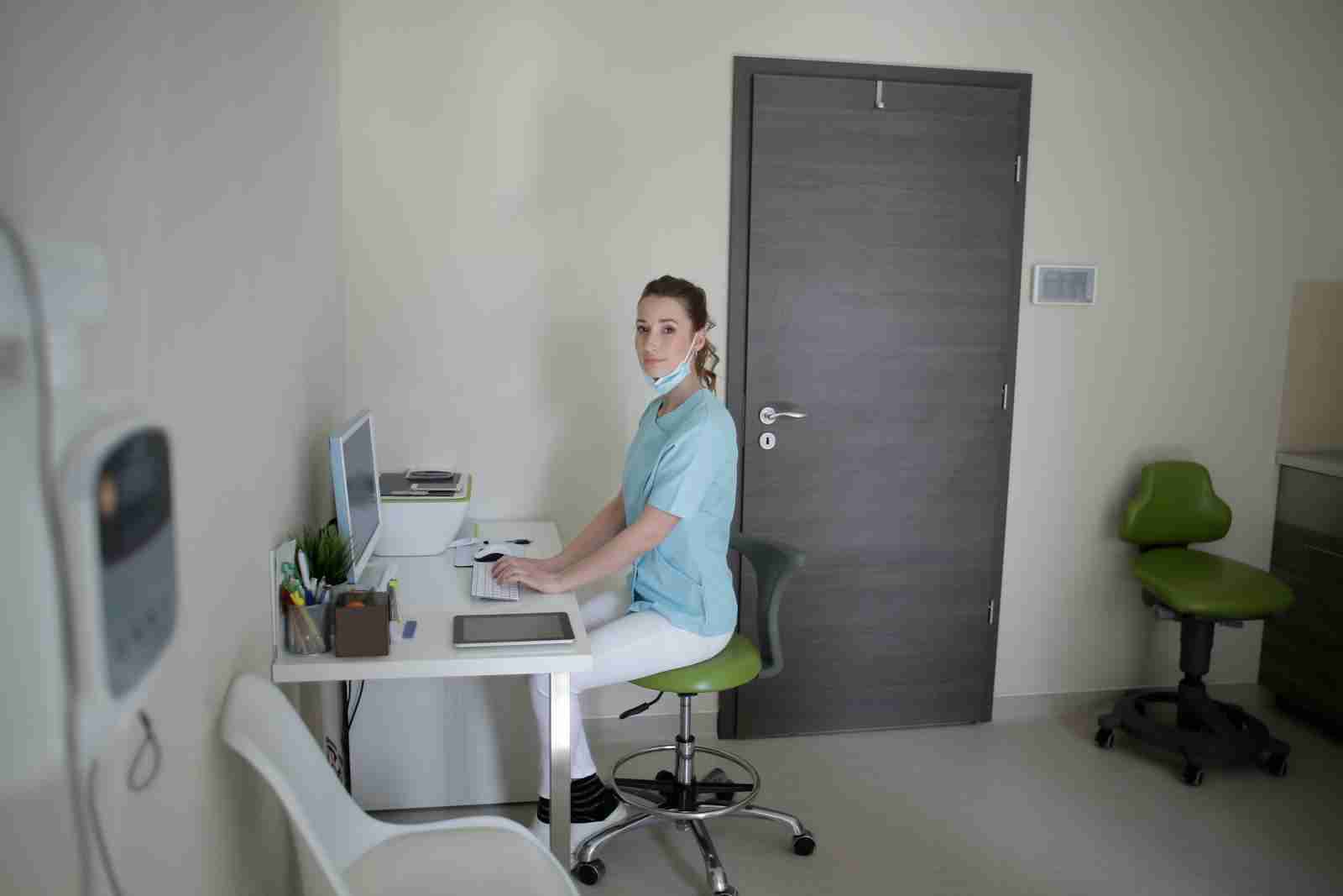Female doctor using desktop computer sitting on chair in clinic